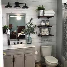 a white toilet sitting next to a sink in a bathroom under a mirror with shelves above it