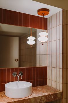 a bathroom sink sitting under a mirror in front of a light fixture on a wall