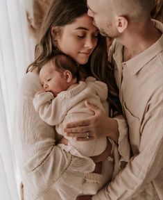 a man and woman holding a baby in their arms