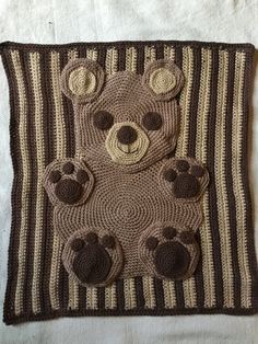 a crocheted teddy bear on a striped blanket