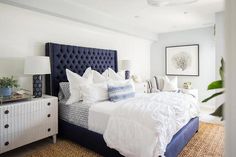 a bedroom with white walls and blue headboard on the bed, along with two nightstands