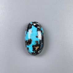 a blue and black bead sitting on top of a white table next to a gray wall