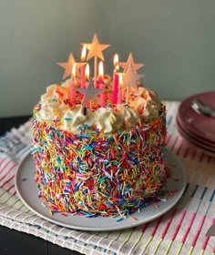 a birthday cake with sprinkles and lit candles