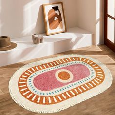 an oval rug on the floor in front of a window with a painting and hat