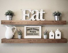 two wooden shelves with some plants and other items on top of them, one shelf has a sign that says eat