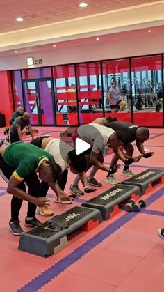 a group of people doing push ups in a gym