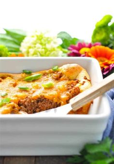 a casserole dish with meat, cheese and green onions