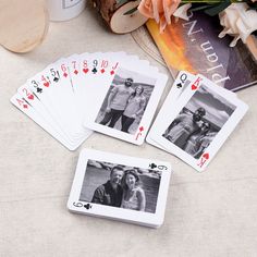 four playing cards sitting on top of a table next to some flowers and a book