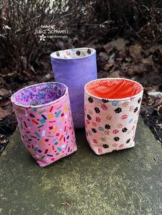 three different colored cups sitting on top of a rock