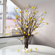 a vase filled with yellow flowers sitting on top of a white table next to a window