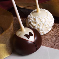 two chocolate covered candies with white frosting and brown bow on top, sitting next to each other