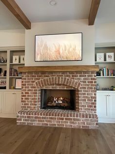 a living room with a brick fireplace and bookcases on the wall above it