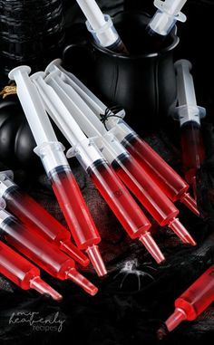 six red and white plastic pens sitting on top of a black table next to a cup