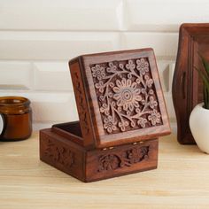 an ornate wooden box sitting on top of a table next to a vase with flowers