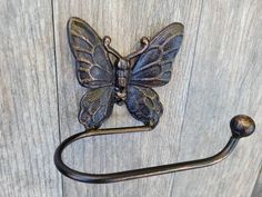 a metal hook with a butterfly on it and a towel ring hanging from the handle