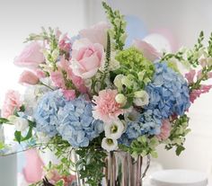 a vase filled with lots of blue and pink flowers