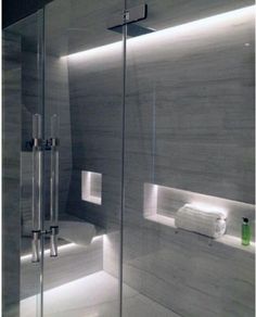 a bathroom with a glass shower door and white towels on the shelf next to it