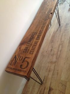 a wooden bench sitting on top of a hard wood floor next to a white wall