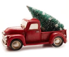 an old red truck with a christmas tree in the back is parked on a white surface