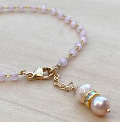 A dainty rosary chain bracelet using faceted Rose quartz beads An iridescent pink freshwater pearl and faceted coordinating glass bead dangles at the close of the gold filled lobster clasp. Dainty Pearl Bracelet With Faceted Round Beads, Dainty Pink Pearl Bracelet With Pearl Charm, Elegant Pink Rosary Bracelet With Round Beads, Bracelet Rosary, Bead Dangles, Rose Quartz Beads, Rosary Chain, Quartz Beads, Quartz Rose