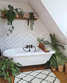 a white bath tub sitting in a bathroom next to a rug and potted plants