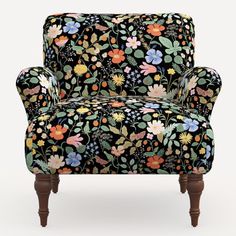 an upholstered chair with colorful flowers and leaves on black fabric, sitting in front of a white background