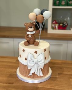 a teddy bear on top of a cake with balloons