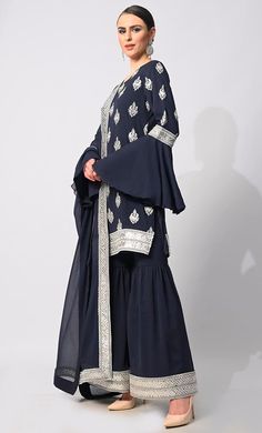 Step into the spotlight with our breathtaking 3-piece Sharara Set, meticulously crafted to elevate your style to new heights. Adorned with intricate silver zari and foil work embroidery, the kurti exudes an aura of timeless elegance, while the heavy foil border on the kurta and Garara hem adds a touch of opulence. Each motif tells a story of exquisite craftsmanship, shimmering gracefully with every movement. The ensemble is completed with a dupatta featuring a matching foil border, tying the loo Elegant Long Sleeve Palazzo Set For Transitional Season, Silver Sets With Zari Work In Traditional Drape, Elegant Silver Party Kurta, Silver Set For Eid Party, Silver Dabka Wedding Sets, Wedding Silver Sets With Dabka Detailing, Silver Wedding Sets With Dabka, Semi-stitched Silver Sets For Eid, Traditional Fitted Silver Sets