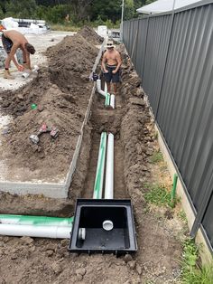 two men are working on an underground drainage system