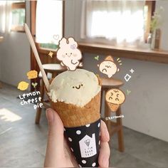 a person holding an ice cream cone with stickers on it in front of a table