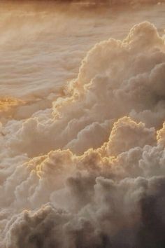 an airplane is flying through the clouds at sunset