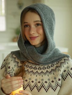 a woman in a sweater holding a lit candle