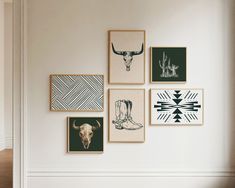 a white wall with several framed pictures on it and a cow skull in the middle