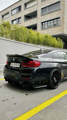 a black bmw is parked in front of a building with yellow lines on the street