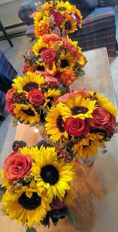 two vases filled with sunflowers and roses on top of a wooden table