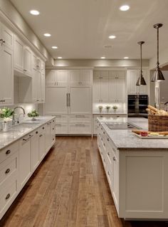 a large kitchen with white cabinets and wooden floors