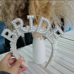 someone is holding the letters bling bling in front of a vase with feathers