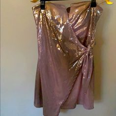 a pink dress hanging on a wall next to a hanger with two yellow flowers