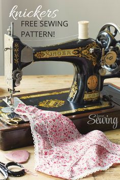 an old sewing machine sitting on top of a wooden table next to scissors and thread