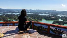 a person sitting on top of a wooden table looking out over a valley and lake