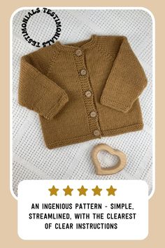 a brown cardigan sweater sitting on top of a bed next to a wooden heart