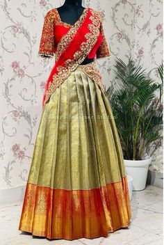 a woman's green and red lehenga with gold trims on it