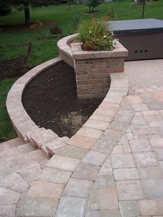 a brick patio with a planter in the middle