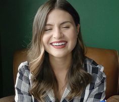 a woman sitting in a chair holding a pair of blue toothbrushes and smiling at the camera