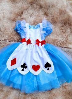 a teddy bear wearing a blue and white dress with playing cards on it's chest