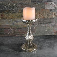 a lit candle sitting on top of a table next to a stone wall and floor