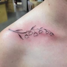 a small tattoo on the chest of a woman's left shoulder, with flowers