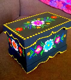 a colorful box sitting on top of a brown couch next to a pink and blue blanket