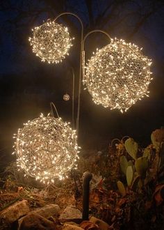 the lights are hanging from the poles in the garden at night time and look like they have snowflakes on them