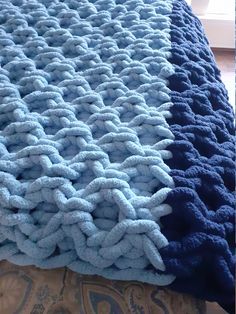 a blue and white blanket sitting on top of a bed